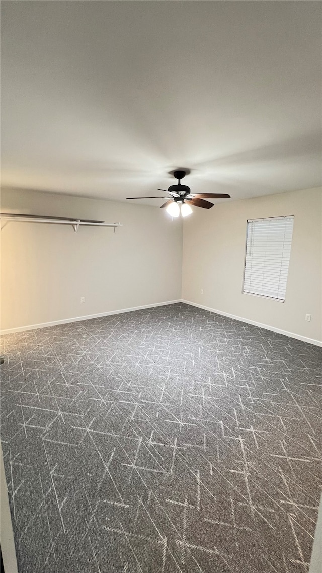 spare room featuring dark colored carpet and ceiling fan