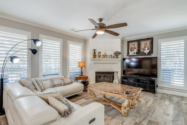 living room featuring light hardwood / wood-style floors, a brick fireplace, ceiling fan, and crown molding