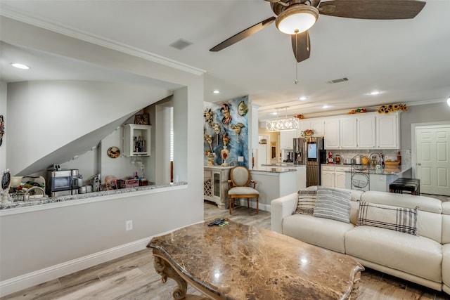 living room featuring ceiling fan, light hardwood / wood-style floors, and crown molding