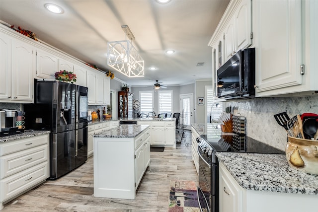 kitchen featuring light wood-type flooring, a kitchen island, crown molding, and black appliances