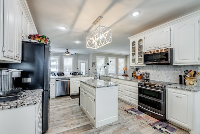 kitchen with white cabinets, a wealth of natural light, a kitchen island, and appliances with stainless steel finishes