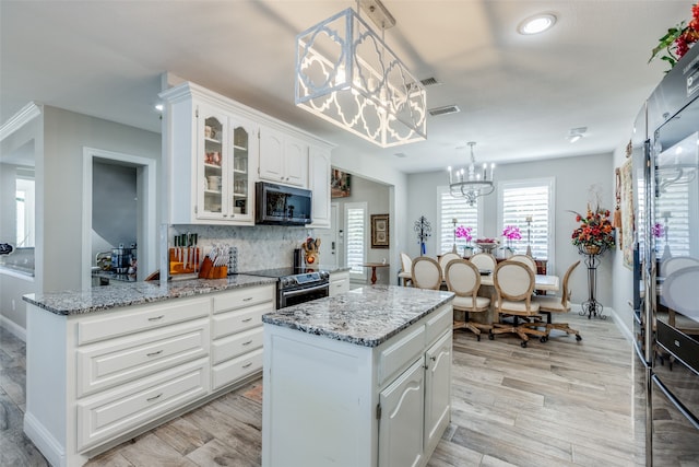 kitchen featuring appliances with stainless steel finishes, white cabinetry, a kitchen island, and pendant lighting