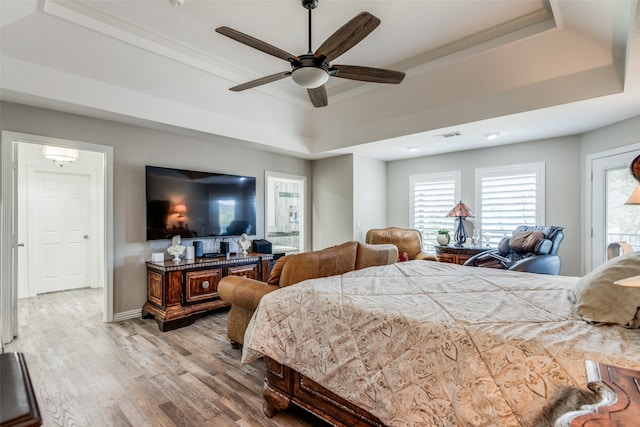 bedroom with ceiling fan, light hardwood / wood-style floors, ornamental molding, and a tray ceiling