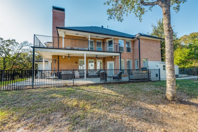 rear view of house featuring a yard, ceiling fan, a balcony, and a patio