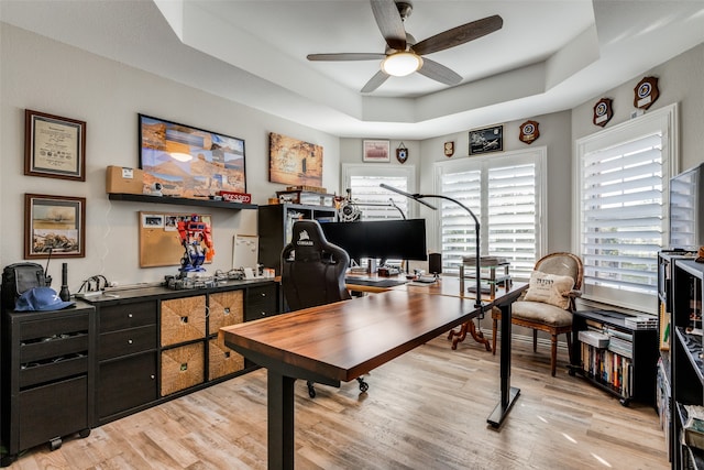 home office featuring a tray ceiling and light wood-type flooring