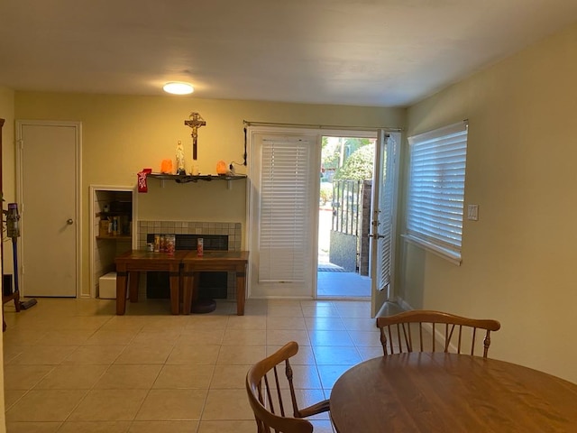 dining space featuring a tiled fireplace and light tile patterned floors