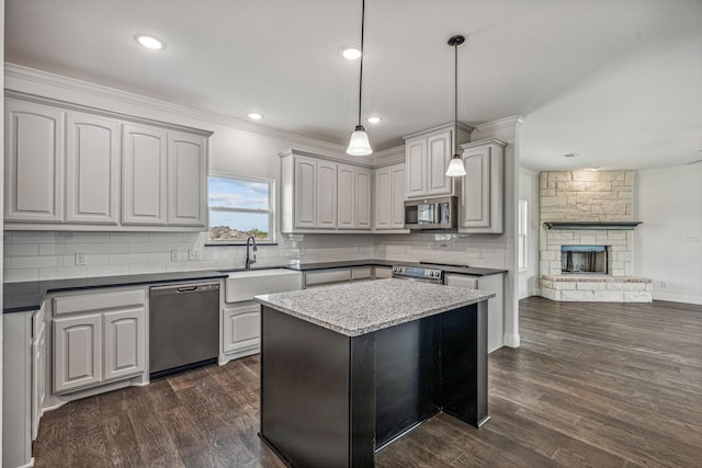 kitchen with stainless steel appliances, dark hardwood / wood-style flooring, pendant lighting, gray cabinets, and a fireplace