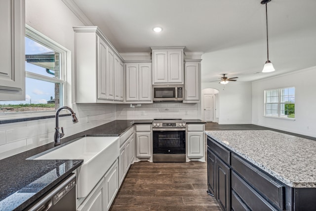 kitchen featuring ceiling fan, dark hardwood / wood-style floors, ornamental molding, appliances with stainless steel finishes, and tasteful backsplash