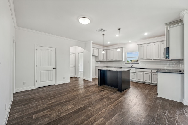 kitchen with a center island, tasteful backsplash, dark hardwood / wood-style floors, crown molding, and pendant lighting