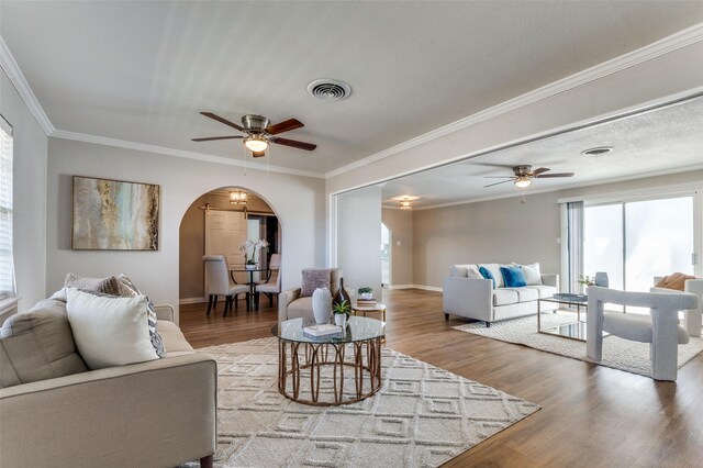 unfurnished living room with a textured ceiling, ceiling fan, light wood-type flooring, and crown molding