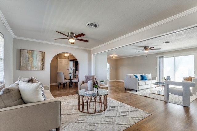 living room with hardwood / wood-style flooring, ornamental molding, and ceiling fan