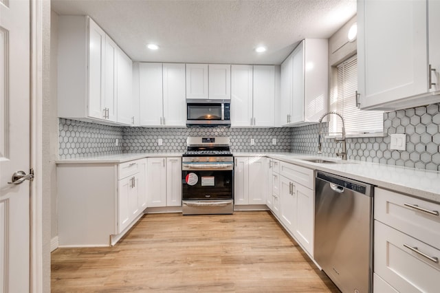 kitchen with white cabinets, light hardwood / wood-style floors, sink, and stainless steel appliances