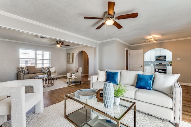 living room with ornamental molding, ceiling fan, a textured ceiling, and light wood-type flooring