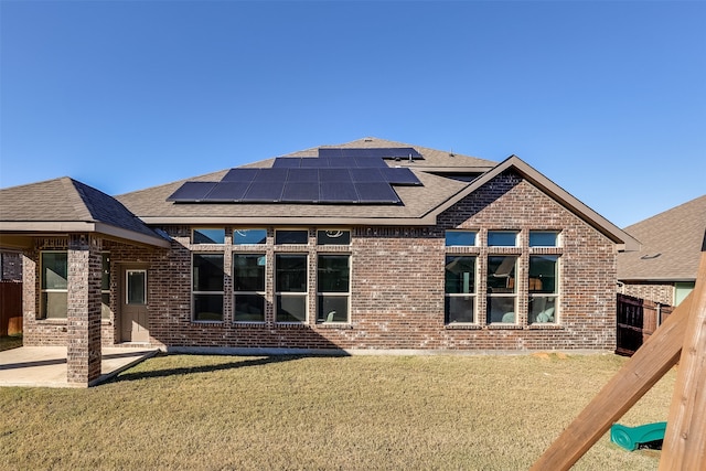 rear view of house featuring a lawn and solar panels