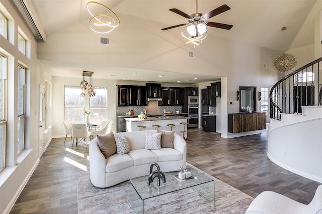 living room with dark hardwood / wood-style flooring, high vaulted ceiling, and ceiling fan with notable chandelier