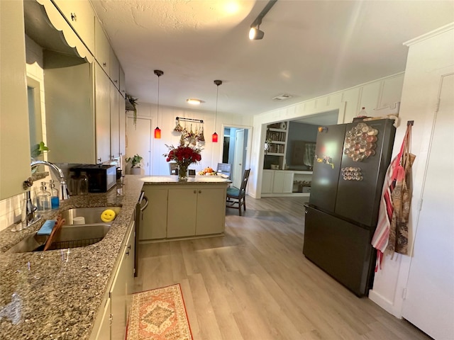 kitchen with sink, hanging light fixtures, fridge, light hardwood / wood-style floors, and kitchen peninsula