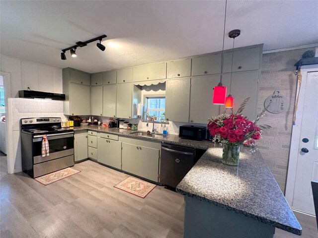 kitchen with sink, range hood, decorative light fixtures, appliances with stainless steel finishes, and light wood-type flooring