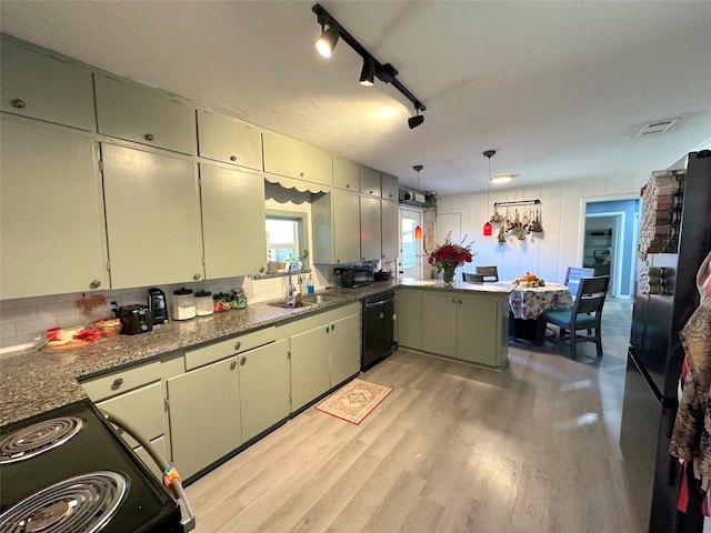 kitchen featuring dishwasher, sink, stainless steel fridge, light wood-type flooring, and range