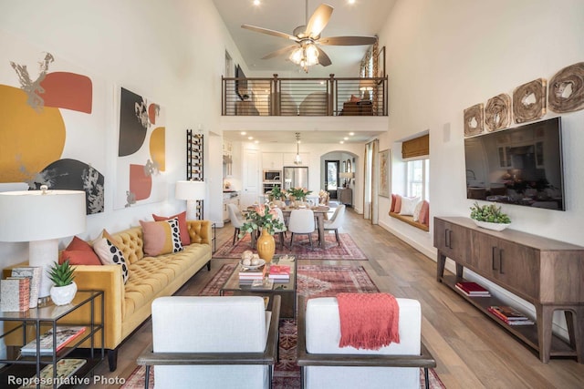 living room featuring ceiling fan, wood-type flooring, and a high ceiling