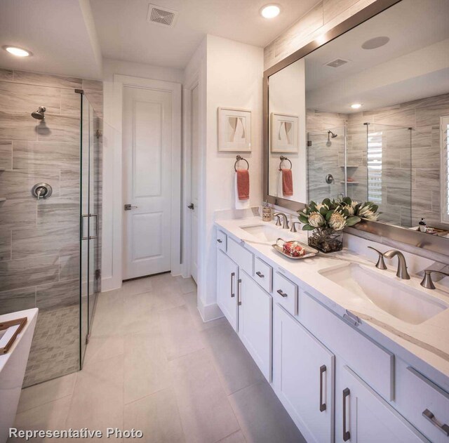 bathroom with tile patterned floors, a shower with door, and vanity