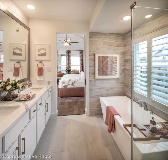 bathroom featuring a wealth of natural light, vanity, tile walls, and a tub