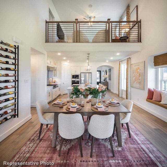 dining room featuring hardwood / wood-style floors, ceiling fan, and a towering ceiling