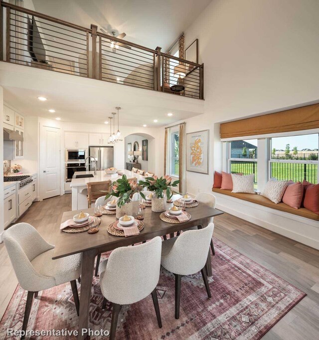 dining space with light hardwood / wood-style floors and a towering ceiling