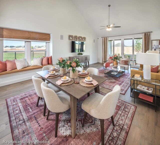 dining space with hardwood / wood-style flooring, high vaulted ceiling, and ceiling fan