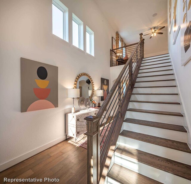 stairway with a towering ceiling and hardwood / wood-style flooring