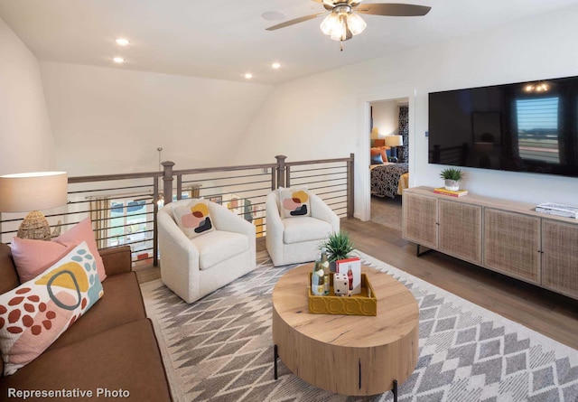 living room featuring ceiling fan, wood-type flooring, and vaulted ceiling