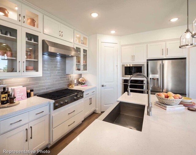 kitchen featuring decorative light fixtures, white cabinetry, stainless steel appliances, and exhaust hood