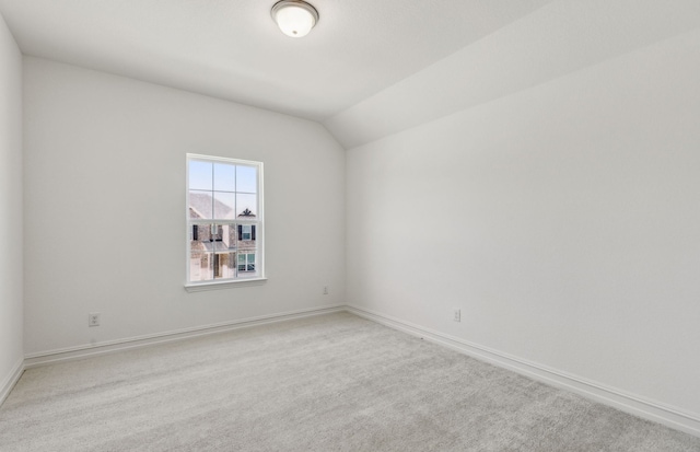 carpeted spare room featuring vaulted ceiling