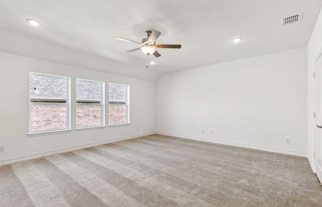 carpeted spare room featuring vaulted ceiling and ceiling fan