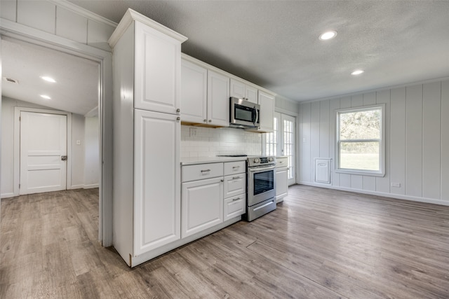 kitchen with white cabinetry, stainless steel appliances, backsplash, a textured ceiling, and light wood-type flooring