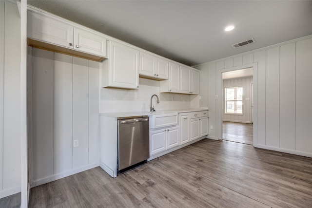 kitchen with white cabinets, light hardwood / wood-style floors, stainless steel dishwasher, and sink