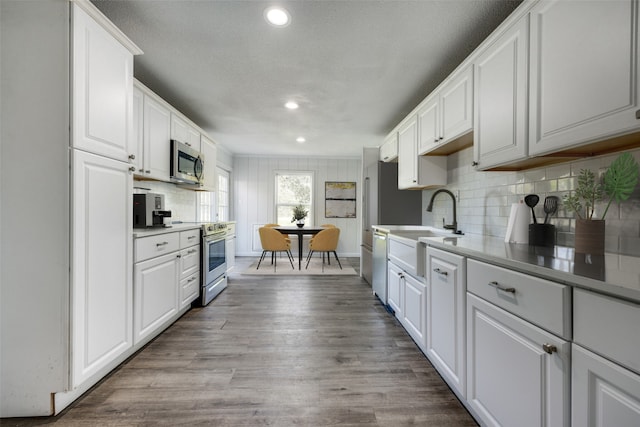 kitchen featuring white cabinetry, sink, light hardwood / wood-style floors, and appliances with stainless steel finishes