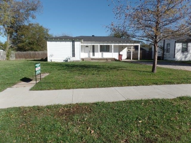 ranch-style home featuring a carport and a front lawn