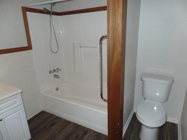 full bathroom featuring shower / bath combination, vanity, tile walls, hardwood / wood-style floors, and toilet