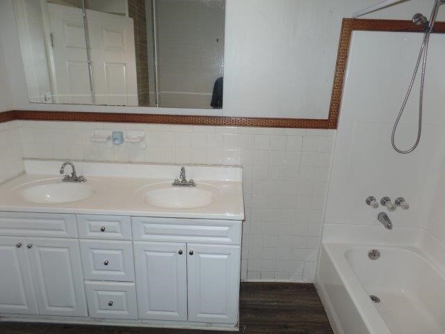 bathroom with shower / bath combination, vanity, hardwood / wood-style flooring, and tile walls