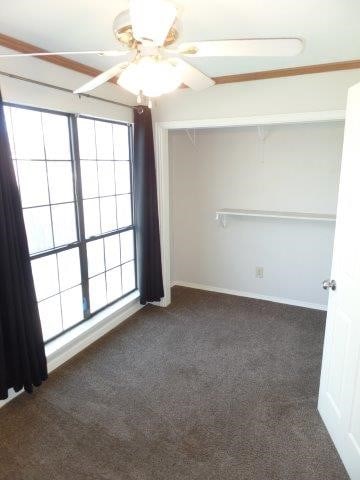 empty room with dark colored carpet and ceiling fan