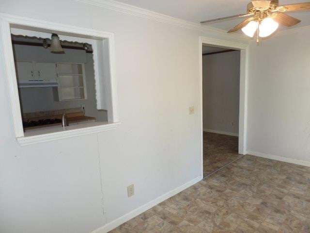 unfurnished room with ceiling fan and crown molding