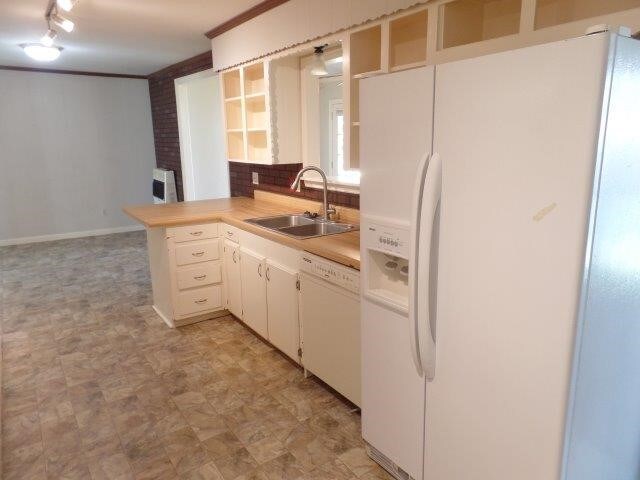 kitchen featuring sink, backsplash, kitchen peninsula, white appliances, and white cabinets