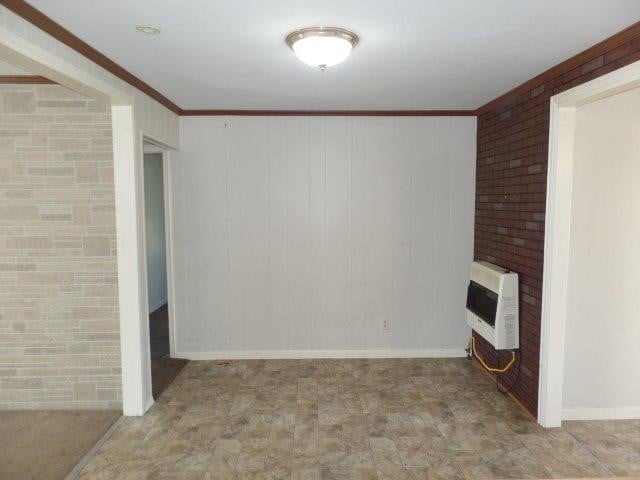 unfurnished living room with crown molding, a fireplace, and heating unit