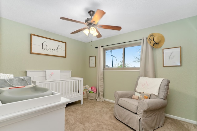 carpeted bedroom with ceiling fan and a crib