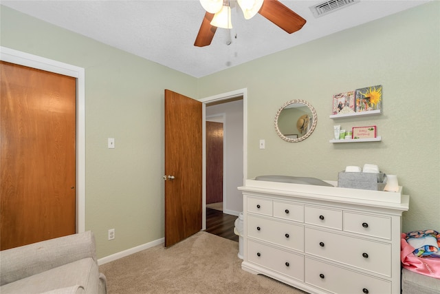 carpeted bedroom featuring ceiling fan and a textured ceiling