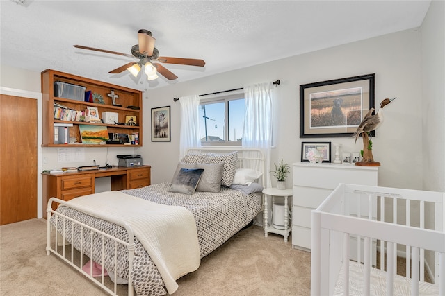 bedroom with ceiling fan, light colored carpet, and a textured ceiling