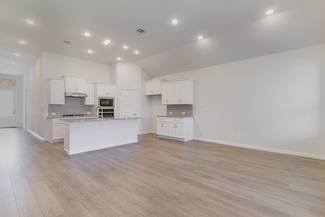 kitchen featuring white cabinetry, black microwave, a kitchen island with sink, and light hardwood / wood-style floors