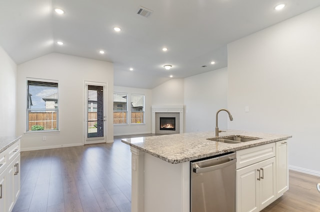 kitchen with white cabinetry, sink, stainless steel dishwasher, vaulted ceiling, and a center island with sink