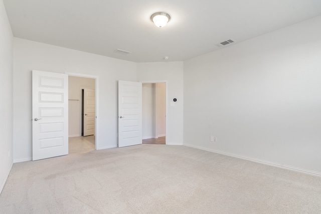 unfurnished bedroom featuring light colored carpet and a closet