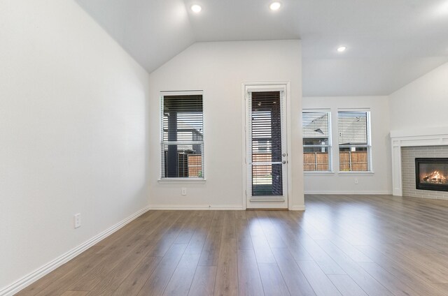 unfurnished living room with hardwood / wood-style floors, a fireplace, and vaulted ceiling